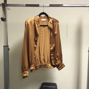  - Guld/kopparfärgad retro blus med axelvaddar, tre knappar saknas. 