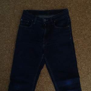 Mörkblå Tiger Jeans med högmidja. Något slitna samt uppsydda några cm.
