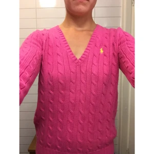  - Supermysig kabelstickad Ralph Lauren tröja i ceris färg. V-ringad och mjuk och skön, tidlös och passar till exempel att dra över en skjorta. Säljer denna som jag fick i present eftersom färgen inte riktigt var i min smak!