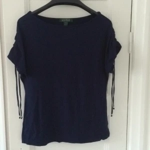  - Mörkblå topp ifrån Ralph Lauren. Guldfärgade detaljer, knyt vid axeln. Använd, ok beg. skick.  
