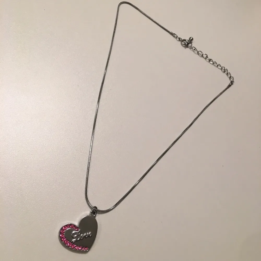 Silvrigt halsband med ett hjärta som detalj, och rosa små diamantstenar. Aldrig använd. Köparen står för frakten 🍂. Accessoarer.