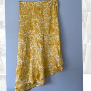 Snedskuren gul sommarkjol - Gul snedskuren kjol i coolt mönster från Ginatricot. Storlek 36. Passar lika bra till vardags som till fest. Använd 1-2 gånger och därav i nyskick!