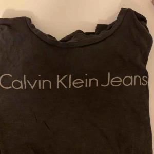  - En Calvin Klein tshirt som jag inte längre använder. Grå tshirt med ett grått tryck. (Samma modell som bilden med tjejen, men inte samma färg) 