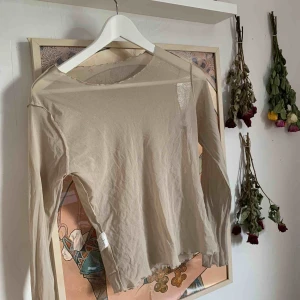  - Genomskinligt tröja som är i en beige nyans. Köpt second hand. Har ett hål i nacken.  