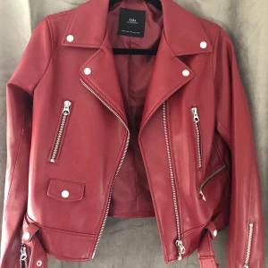 Röd skinnjacka  - Röd skinnjacka med silverdetaljer. Storlek Large dock passform som en medium. I fint skick då jag använt den vid få tillfällen. Köparen står för frakten 