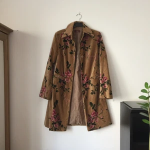  - Mycket vacker kappa, sanmetsaktigt mjukt material. Gyllenbrun med rosor. Södermalm, rock, musiker-boho chic -feeling. Den är lite sliten vid ena fickan (något jag inte sett förut). Syns på en av bilderna och bara om man tittar nära. 