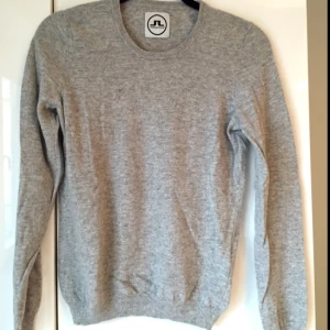  - Ljusgrå tröja i 100% cashmir från J. Lindeberg. Ett litet hål i nacken vid etiketten, men det syns inte vid användning. Tight fit på modellen, så L är som S/M.