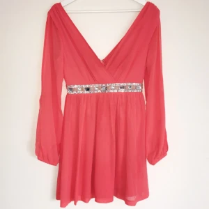  - Korallröd klänning från Nelly endast använd 1 gång. Längden är till ca halva låret, något längre.