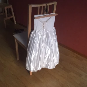  - Vit klänning med ballongkjol i siden och vit mudd över bysten. Använd endast en gång och i mycket fint skick. Passar bra som studentklänning!