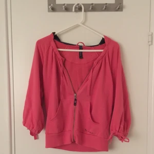  - Gullig mjuk rosa kofta från Bondelid! 3/4 ärmar med snörning längst ut och vid kragen. Luva med mörkblått tyg i. Köpare får betala frakt eller mötas upp i Stockholm :) Kan ge fler bilder vid förfrågan!