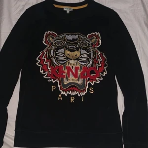 Kenzo tröja - Svart Kenzo tröja med röda, guldiga och silvriga detaljer storlek XS, inköpt i Paris för ett tag sedan för närmre 300 €, väldigt sparsamt använd.  Den som budar högst får den, börjar på 1100 kr