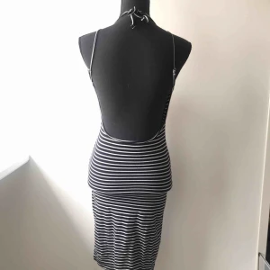  - Randig klänning med öppen rygg. Halterneck men knytning i bak och reglerbara axelband. Klänningen går över knäna. I mycket fint skick! Köparen står för frakten 🦋