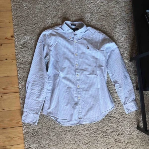  - Vit- och blårandig skjorta från Ralph Lauren. Är knappt använd och i väldigt gott skick. Originalpris är ca 1000kr.