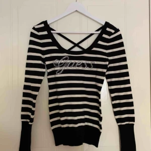 Randig Guess tröja i storlek S - Svart/vit randig tröja från Guess, med Guess skrivit i glitter på framsidan & korsande band i ryggen. Säljer likadan tröja i grå/rosa, storlek xs. Köp båda för 250 kr tillsammans eller 150 kr styck. Frakt ingår.