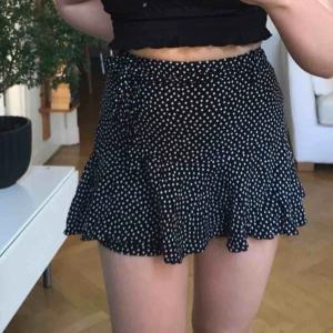  - Svarta shorts som ser ut som en kjol (så najs då man aldrig behöver oroa sig för vind) med små vita prickar med dragkedja på sidan och matchade skärp, knappt använd :) OBS! Budgivning pågår skriv för att veta nuvarande pris :)