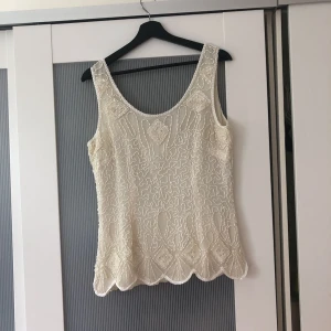  - Sjukt fin blus från Frank Usher. Den är gjord i silke med dragkedja där bak och massor av pärlor och paljetter broderade i tyget. Perfekt till fest och finare tillfällen. Den har aldrig blivit använd.