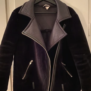 Jacka från HM strl 38 - Mysig och varm jacka med ”plysch” och läder detaljer. Strl 38 men passar även till 42. Oversize. Haft den i 2 år men använd fåtal gg. Bra skick, saknar dock ett bälte. Tyckte de va finare utan :)