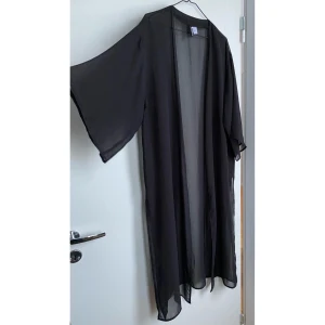 Mesh-kimono i stl S - Svart kimono av mesh i stl S. Stor i storleken och slits i sidan. Oanvänd och i fint skick.