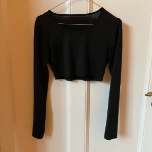 Humana svart långärmad magtröja - Elastiskt tyg, sitter nära kroppen. Snygg rund ringning. Från humana
