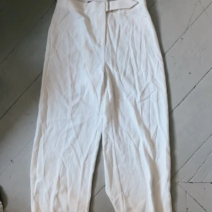 VITA KOSTYMBYXOR - Vita kostymbyxor med gulddetalj. Har en liten fläck därför säljer jag dem för billigt pris. Möts på Södermalm och vid frakt står köparen för kostnad!