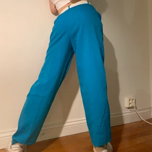 Turkos blå vintage retro 80s högmidjade raka kostymbyxor  - Turkos blåa 80s/90s vintage högmidjade raka kostymbyxor med perfekt passform över rumpan och som går ner rakt över benen 💙 Detta är de bästa statement byxorna att ha till ett par vita sneakers och en tight graphic tee/baby tee, vita eller blåa accessoarer eller om man vill lägga in en persiko rosa komplementfärg för att göra ett riiiktigt statement! Byxorna har följande mått: midjemått 71 cm, byxlängd: 98 cm (kan läggas ned till 103 cm), innerbenslängd: 66 cm