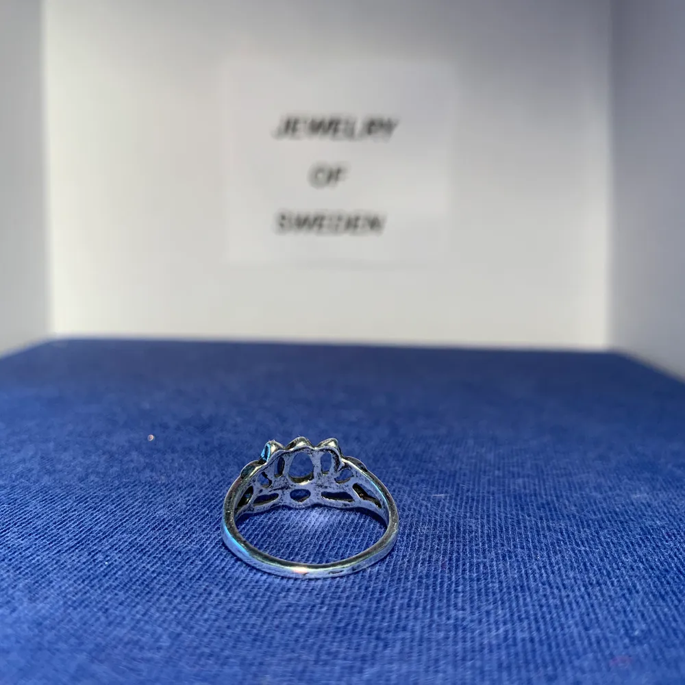 En ring med ett lite blomaktigt motiv. Ringen är i rostfritt stål. . Accessoarer.