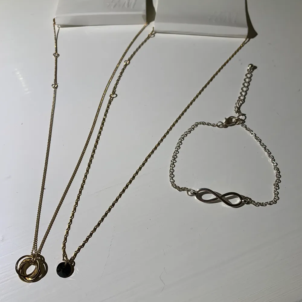 2 oanvända halsband, ett med ringar och ett med en svart sten. Silver armband storlek M-L i storlek med evighetstecknet, alla för 20. Accessoarer.