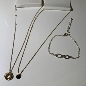 Smycken - 2 oanvända halsband, ett med ringar och ett med en svart sten. Silver armband storlek M-L i storlek med evighetstecknet, alla för 20
