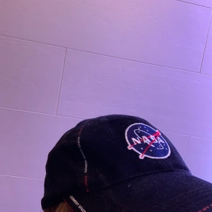 Nasa Keps  - Nasa keps, Den sitter bra på huvudet och det går att ändra storlek. Skärmen är rörlig vilket är skönt. Skicket är bra eftersom att den är i nyskick.                                              25kr + frakt  (står inte för postens slarv)      Är bered på att ändra pris! 