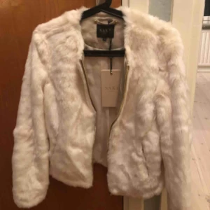  - Vit superfin och mjuk fusk pälsjacka med guldig dragkedja. Aldrig använd då den tyvärr är lite för stor för mig. Storlek 36, nypris 1299kr, sälj för 400kr och då ingår frakt. Kan även mötas upp i Uppsala 