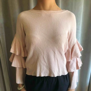  - En ljusrosa tröja med volanger. Köparen står för frakten