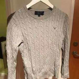  - Grå kabelstickad u-ringad tröja från gant, använd en del men fortfarande i väldigt fint skick! Köparen står för frakt, skriv för fler frågor! :D