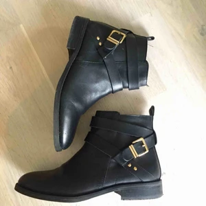 Snygga svarta skinnskor med gulddetaljer - Snygga svarta skinnskor med gulddetaljer. inköpa på din sko. Jättefint skick. Används enstaka gånger. Nypris: 899:-