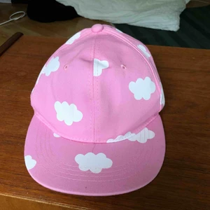  - Rosa keps med små vita moln. Justerbar rem där bak, frakt tillkommer!