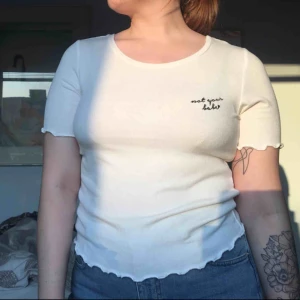  - Vit t-shirt med texten ”not your babe”. 
