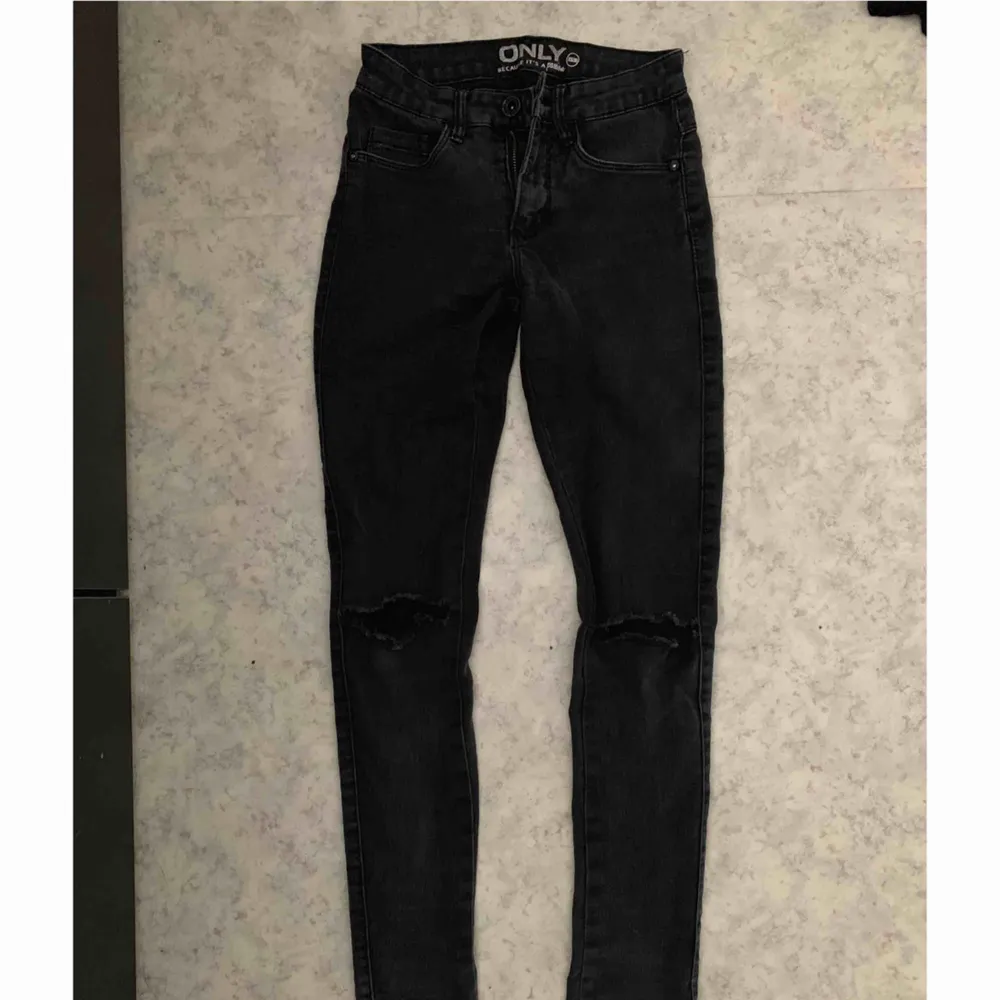 Ett par mörkgråa jeans med hål i knäna,   köpta ifrån Nelly.  Storlek XS. Jeans & Byxor.