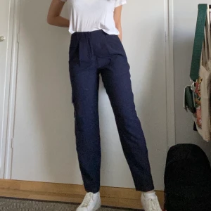 Byxor från Carin Wester - Snygg och skön marinblå byxa från Carin Wester! Byxans passform är som en mer flowy kostymbyxa och har en ficka på sidan av den. Säljer då jag aldrig använder den! (Köparen står för frakt)