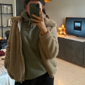 Teddyjacka - Beige/ljusbrun teddyjacka med kgrage, dragkedja och fickor. Går att spänna åt. Märke: H&M storlek XS. Buda i kommentarerna eller skriv till mig privat! Frakt tillkommer om mötas inte är möjligt!  
