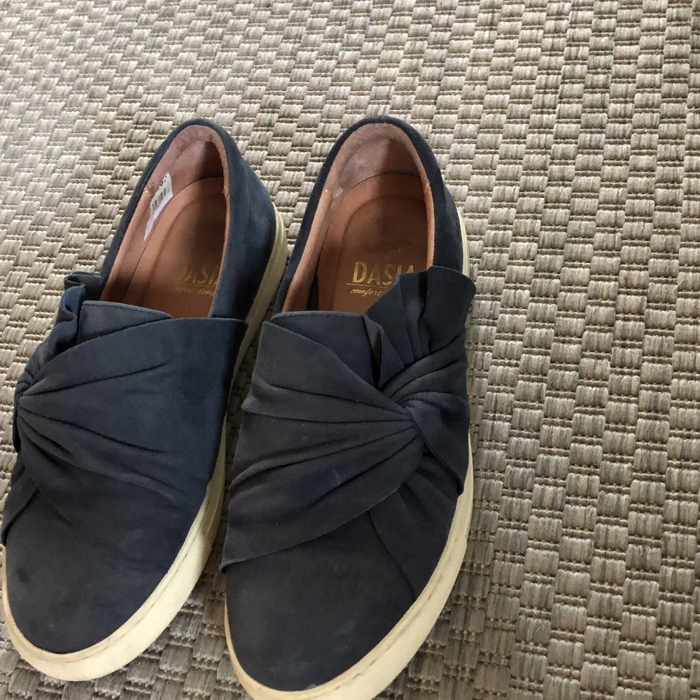 (GRATIS FRAKT) Fina marinblå slip-on sneakers från Dasia. Mycket fint skick då de inte är använda så mycket. Normal slitning på sulan:). Skor.