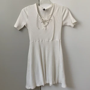 Klänning från Divided H&M  - Klänningen är vit och ribbad med korsade snören vid bysten. Storleken är 34 och klänningen. 