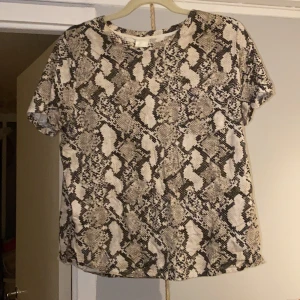 Ormmönstrad tröja - Ormmönstrad tröja med en ficka på bröstet. Aldrig använd. Slutsåld på hemsidan, storlek M. Säljer för 60kr frakten ingår i priset!