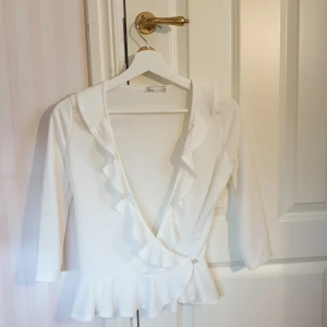 Omlott topp från Nelly - Vit omlott topp från NellyTrend. Aldrig använd. Volanger längs urigningen, trekvartsärm. Hör av dig vid intresse💫💕