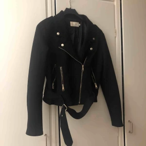  - Jacka i mocka material med många detaljer som fickor och bältet nertill. Sitter som en storlek 40