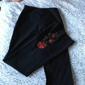  - Svarta byxor med en röd detalj av rosor