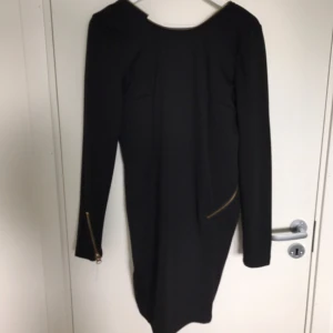  - Cool svart klänning med dragkedja runt hals och rygg. Djup i ryggen vilket ger den perfekta party-looken. Fin till både nyår, fest och vardag. Köparen står för frakten :) 