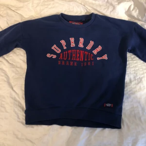 Superdry collage tröja i storlek: UK 12 - Säljer en väldigt snygg mörkblå collage tröja med märket av superdry. I okej skick, lite nopprig men ingenting man tänker på. köpte den för 400kr och säljer den för 50