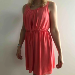  - Aprikosfärgad klänning med lite detaljer på axlarna. Perfekt att använda på bland annat bröllop/dop.  Använd fåtal gånger. Säljes pga flytt. Går att mötas upp i Stockholm, annars tillkommer frakt. 