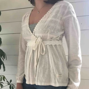  - Vit unik kofta från Odd Molly. Använd ca 3 gånger. Jätte gullig med guld pärlor runt v-ringningen, omlottknytning och söta detaljer på överdelen.   Frakt tillkommer