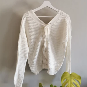 Stickad tröja med snörning i bak - Stickad tröja från Nelly, snörning på ryggen. Köparen står för frakt. 