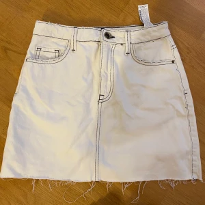 Jeans kjol från zara - Säljer denna as snygga jeans kjol från zara. Vit med svarta söm detaljer, så najs! Knappt använd. Är 167 och brukar oftast ha XS i kjolar och denna är en aning liten, så den blir tight! Men i längden är den bra. 